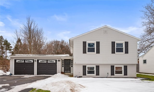 split level home with a garage and aphalt driveway