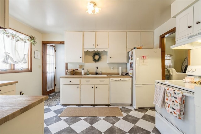 kitchen with under cabinet range hood, white appliances, a sink, light countertops, and light floors