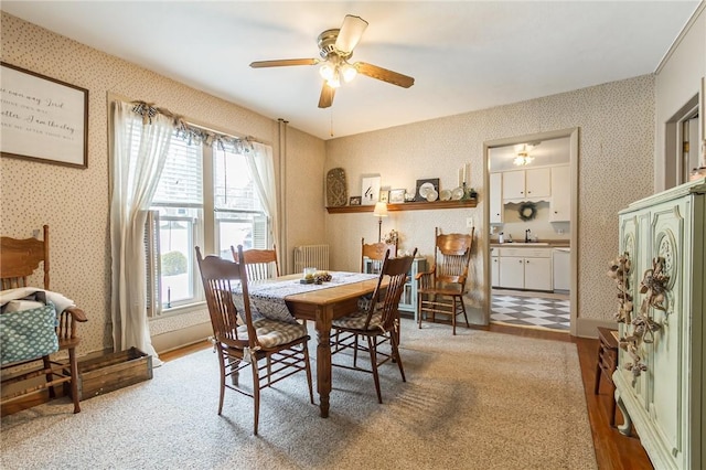 dining space featuring radiator, wallpapered walls, ceiling fan, and wood finished floors