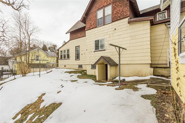 snow covered rear of property featuring fence