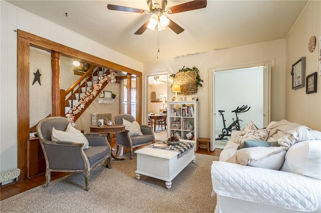 living room featuring ceiling fan, ornamental molding, wood finished floors, and stairs