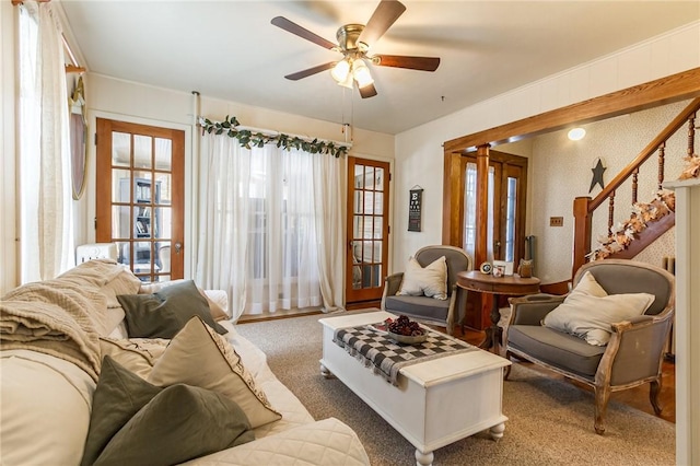 carpeted living area featuring ceiling fan and stairs