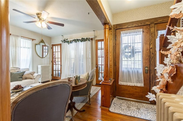 interior space featuring wallpapered walls, ceiling fan, radiator heating unit, and wood finished floors