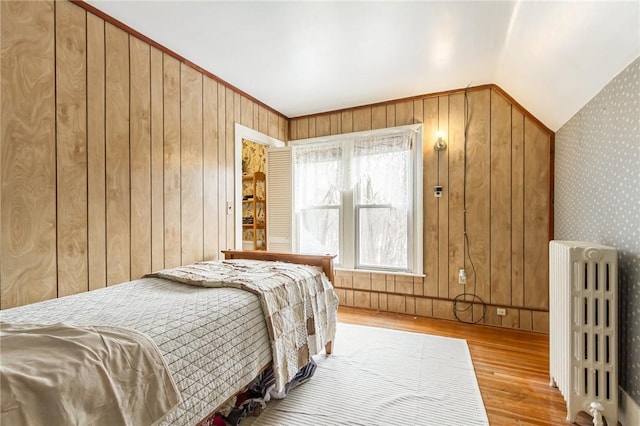 bedroom featuring radiator, vaulted ceiling, and wood finished floors