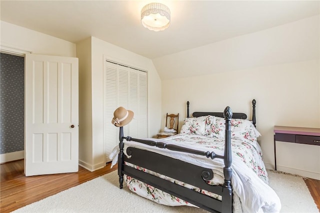 bedroom featuring a closet, vaulted ceiling, baseboards, and wood finished floors