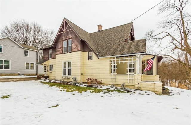 snow covered house featuring a shingled roof and a chimney