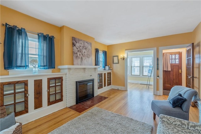 living area featuring a wealth of natural light, a fireplace, and wood finished floors