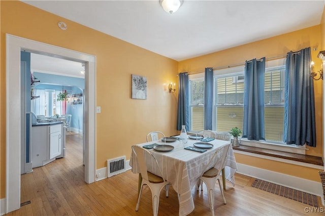 dining area featuring light wood-type flooring, visible vents, and baseboards