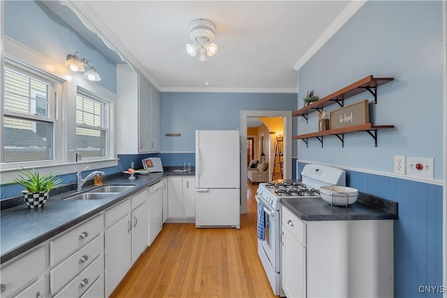 kitchen with dark countertops, ornamental molding, white cabinetry, a sink, and white appliances