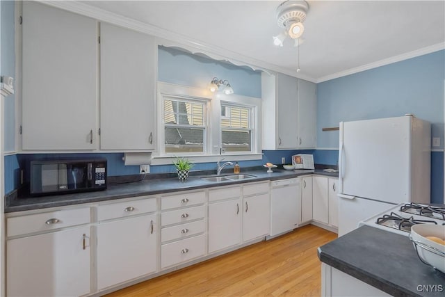 kitchen featuring dark countertops, white appliances, a sink, and light wood-style flooring