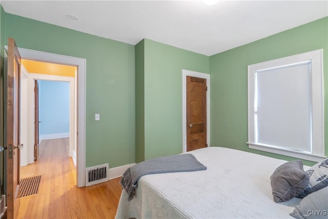 bedroom with baseboards, visible vents, and light wood finished floors