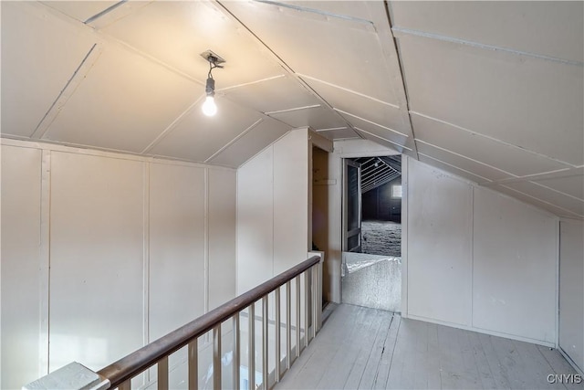 additional living space featuring vaulted ceiling and light wood-type flooring