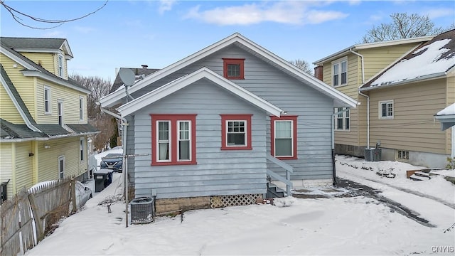 snow covered property with fence and central air condition unit