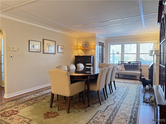 dining room with arched walkways, crown molding, wood finished floors, and baseboards