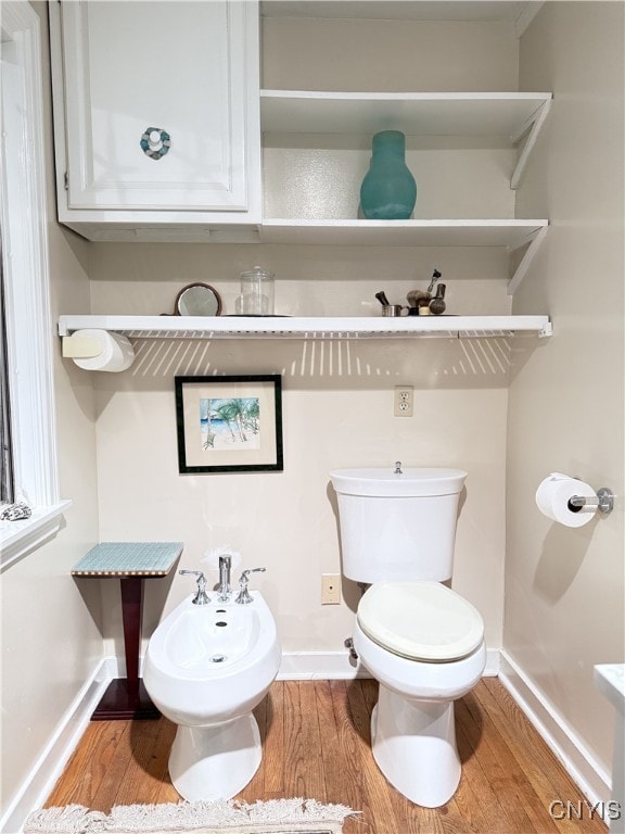 half bathroom featuring toilet, baseboards, and wood finished floors