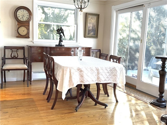 dining area featuring a wealth of natural light, light wood-type flooring, a chandelier, and a baseboard heating unit