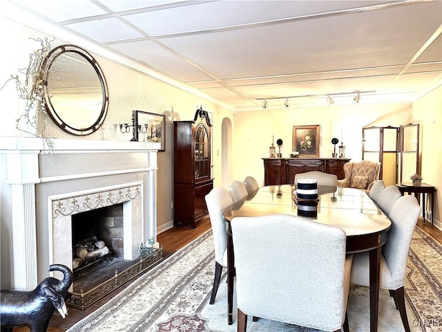 dining room with baseboards, arched walkways, wood finished floors, and a high end fireplace