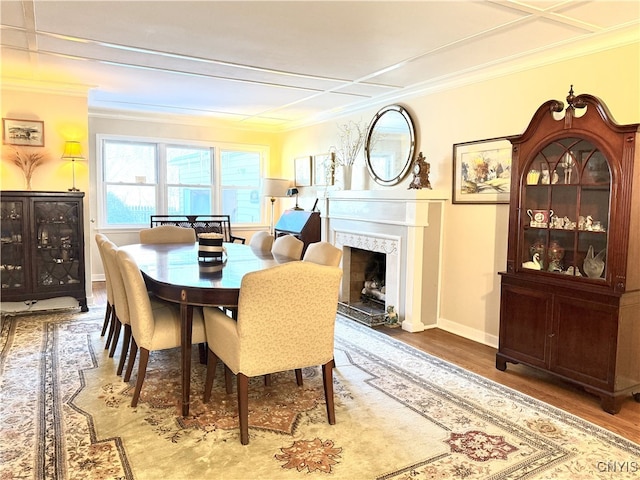 dining space with a high end fireplace, crown molding, baseboards, and wood finished floors