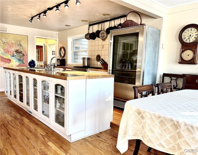 kitchen featuring a sink, white cabinetry, glass insert cabinets, and wood finished floors