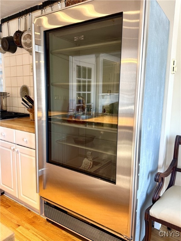 details with wine cooler, decorative backsplash, light wood-style flooring, and white cabinets