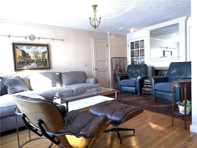 living area with a textured ceiling, a fireplace, wood finished floors, and a notable chandelier