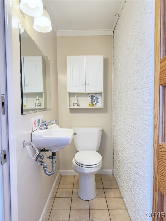 bathroom with toilet, tile patterned flooring, ornamental molding, and baseboards