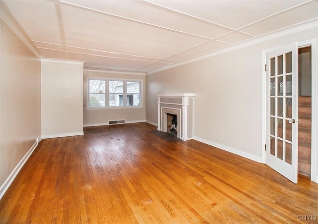 unfurnished living room featuring hardwood / wood-style floors, a fireplace with flush hearth, visible vents, and baseboards