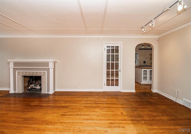 unfurnished living room featuring a fireplace with flush hearth, arched walkways, wood finished floors, and baseboards