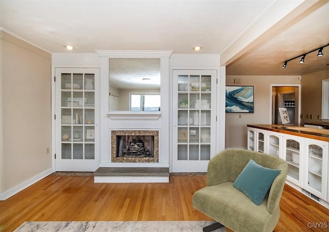 sitting room featuring a fireplace, baseboards, and wood finished floors