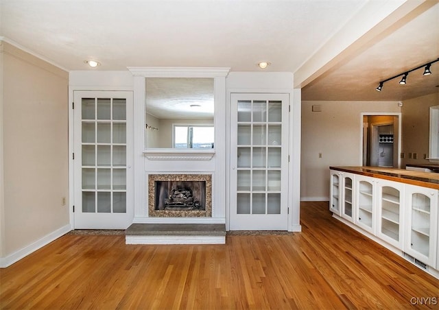 unfurnished living room featuring a fireplace, wood finished floors, and baseboards