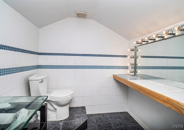 bathroom with toilet, visible vents, tile walls, and lofted ceiling