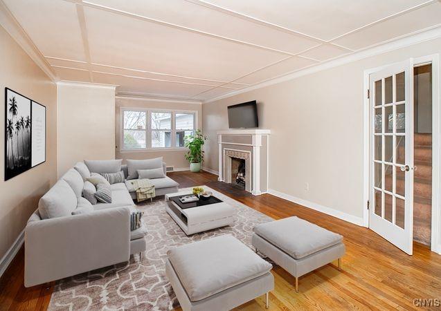 living room featuring crown molding, baseboards, and wood finished floors