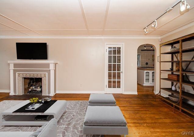 living room featuring arched walkways, a fireplace, wood finished floors, and baseboards