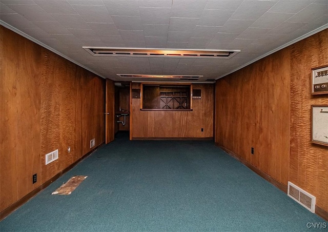 unfurnished room featuring carpet, visible vents, and wood walls