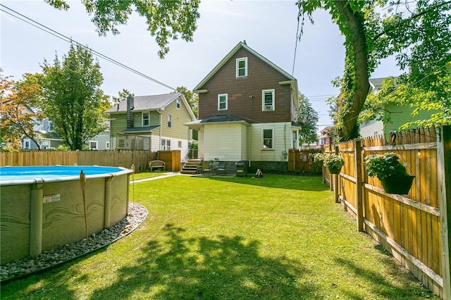 back of house with a lawn, a fenced backyard, and a fenced in pool