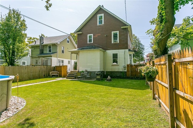 back of property with a fenced backyard and a yard