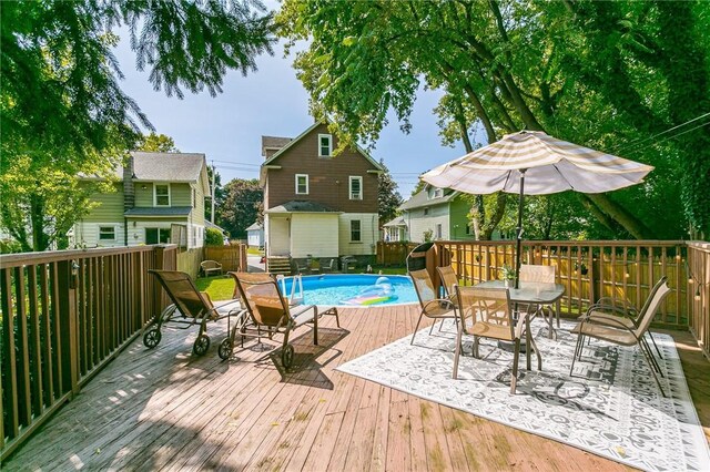 exterior space featuring a deck, a fenced in pool, and outdoor dining space