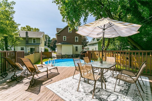 view of swimming pool featuring outdoor dining space, a wooden deck, and a fenced in pool