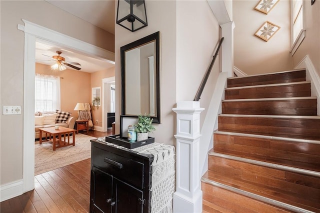 stairway featuring baseboards, hardwood / wood-style flooring, and a ceiling fan