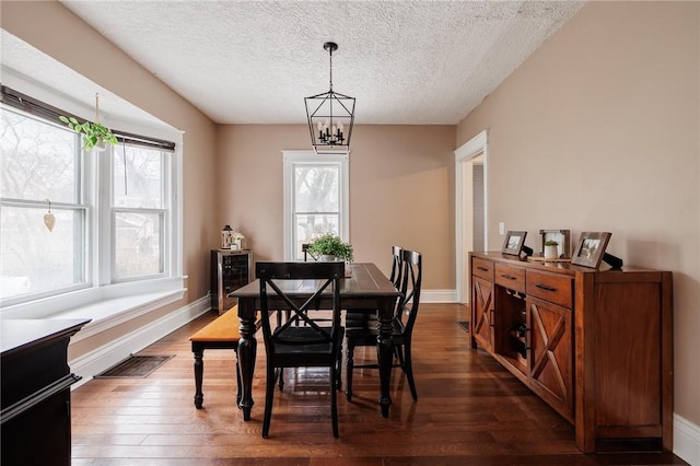 dining area with baseboards, dark wood-style flooring, visible vents, and a notable chandelier