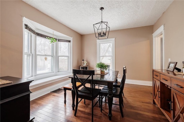 dining area featuring dark wood-style floors, baseboards, a chandelier, and a wealth of natural light