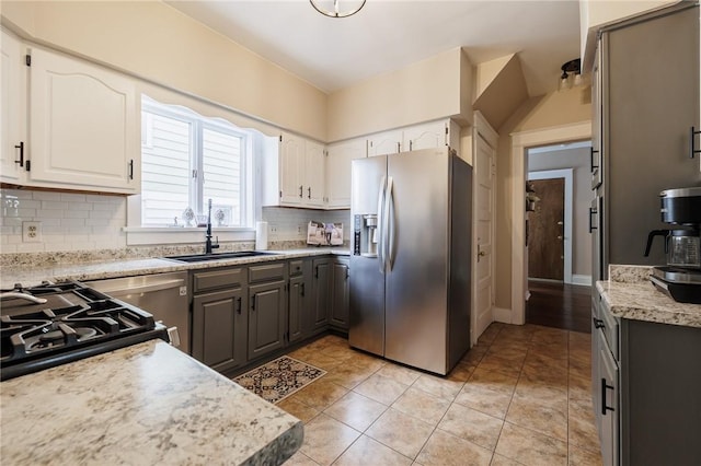 kitchen with gray cabinetry, a sink, white cabinetry, decorative backsplash, and stainless steel fridge