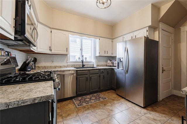 kitchen featuring tasteful backsplash, white cabinets, appliances with stainless steel finishes, light countertops, and a sink