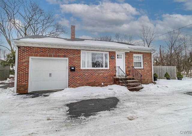 view of front of property with a garage, brick siding, a chimney, and fence