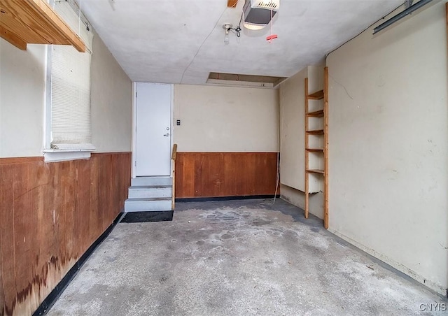 garage with a garage door opener, a wainscoted wall, and wood walls