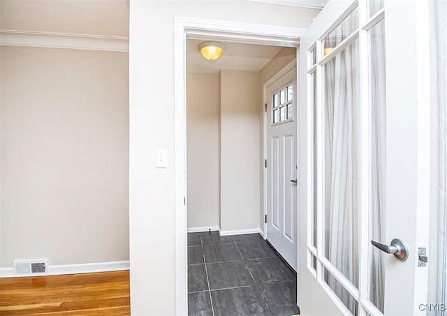 interior space with baseboards, visible vents, and crown molding