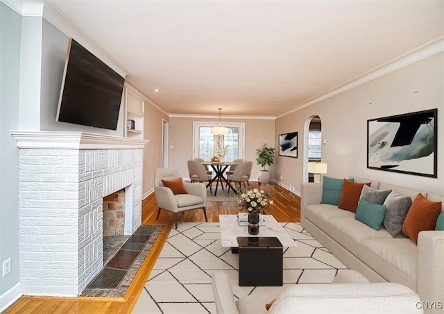 living room featuring baseboards, light wood-type flooring, and crown molding