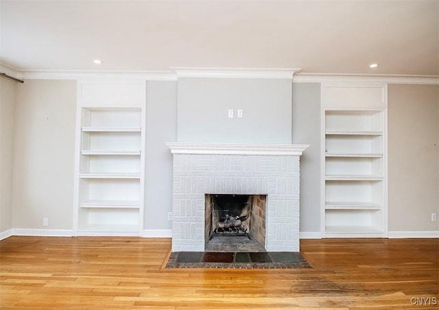 unfurnished living room with baseboards, crown molding, wood finished floors, and built in features