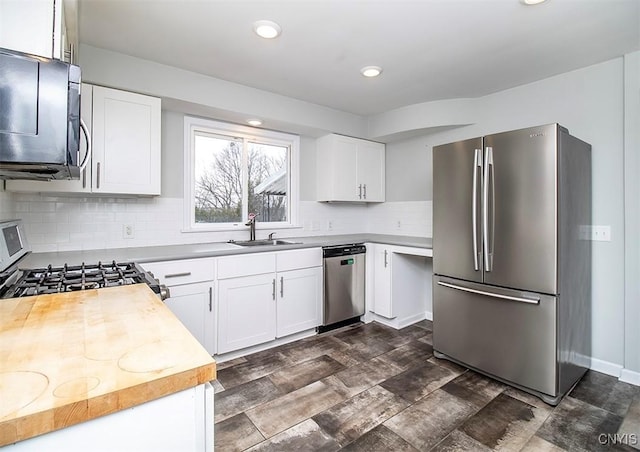 kitchen with stainless steel appliances, tasteful backsplash, a sink, and white cabinetry