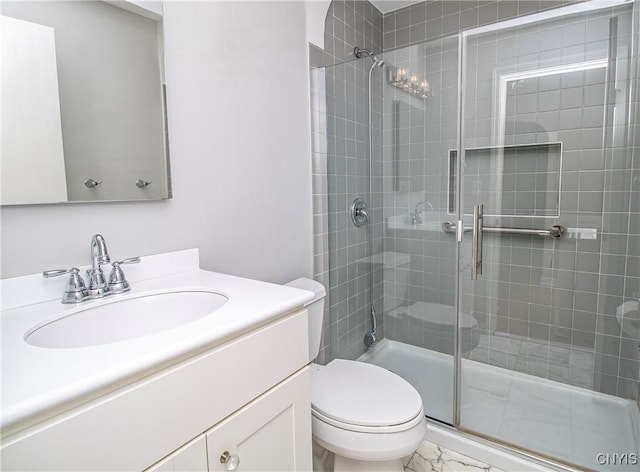 bathroom featuring toilet, marble finish floor, a shower stall, and vanity